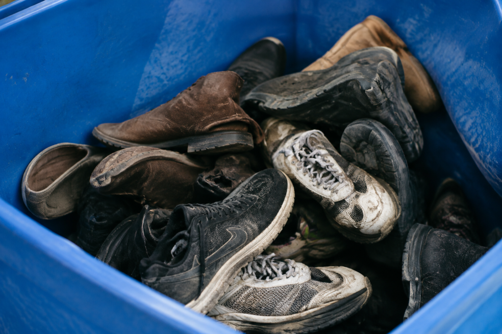 Chaussures usees en tas dans bac bleu