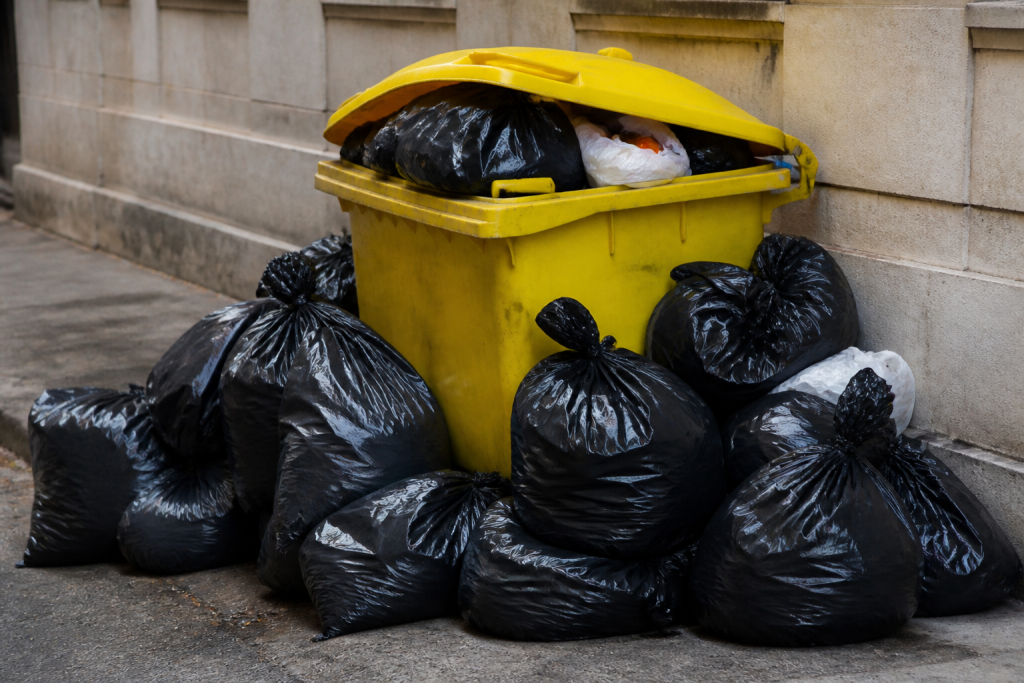 Conteneur jaune plein entoure de sacs noirs